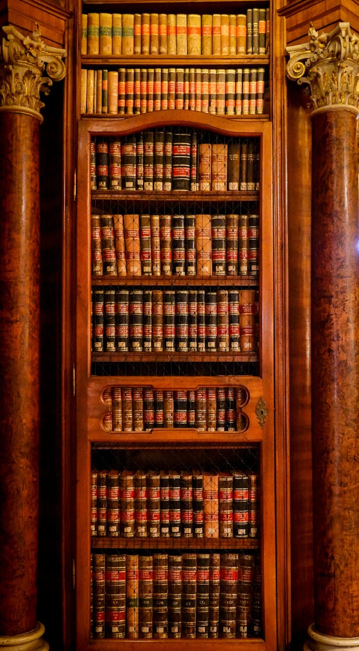 gallery-2 Tall wooden bookshelf filled with vintage books, flanked by decorative columns.