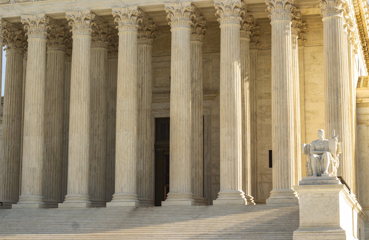 The Supreme Court of the United States with iconic marble columns and statue, captured in natural light.